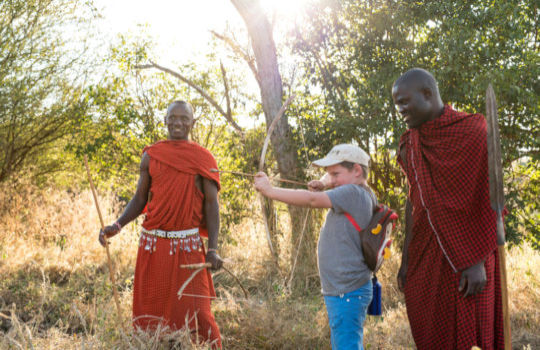 Kind met pijl en boog en Masai krijgers