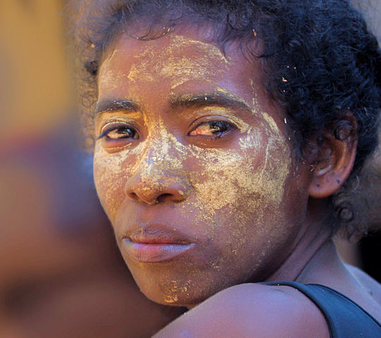 Vrouw met beschilderd gezicht tijdens reis door Madagascar